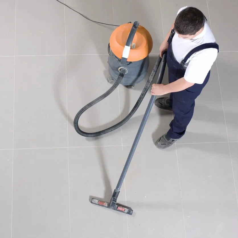 Man vacuuming a smooth floor with an industrial vacuum cleaner.